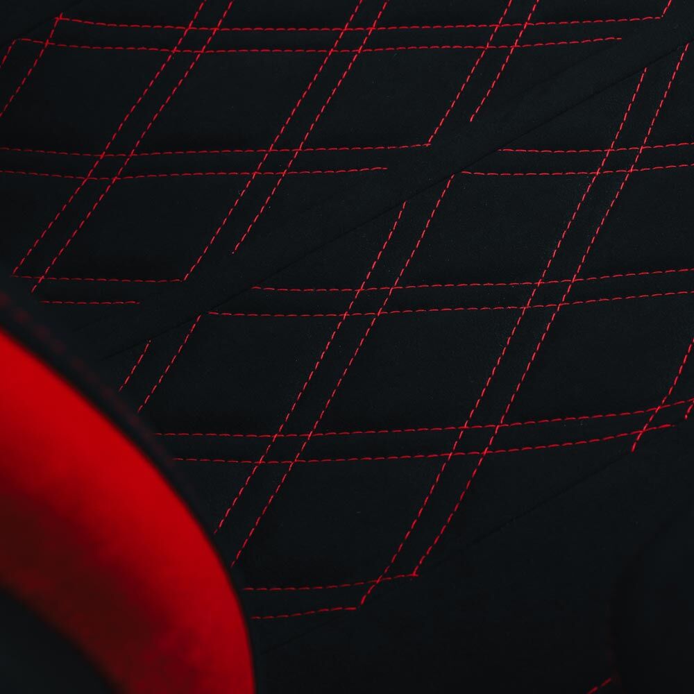 Nahaufnahme eines schwarzen Stoffs mit roten Nähten, in Rautenform verläuft.
