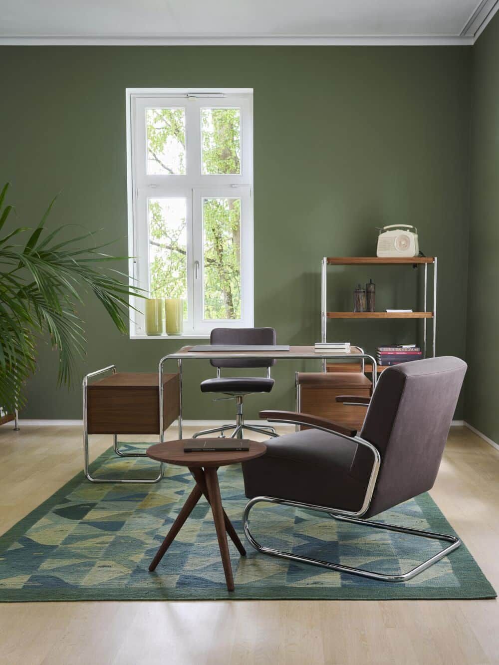 Moderne Büroumgebung mit ergonomischem Schreibtischstuhl, gemütlichem Sessel, grünem Teppich und natürlichem Licht.