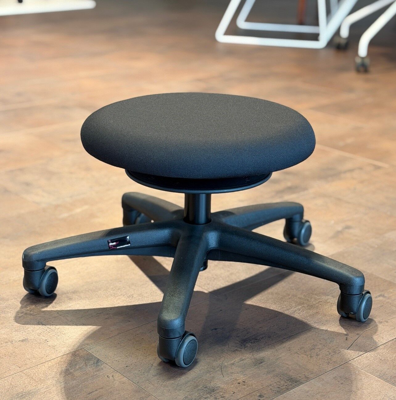 Ergonomischer Bürostuhl mit rundem Sitz auf rollbarem, drehbarem Gestell. Geeignet für dynamisches Sitzen.