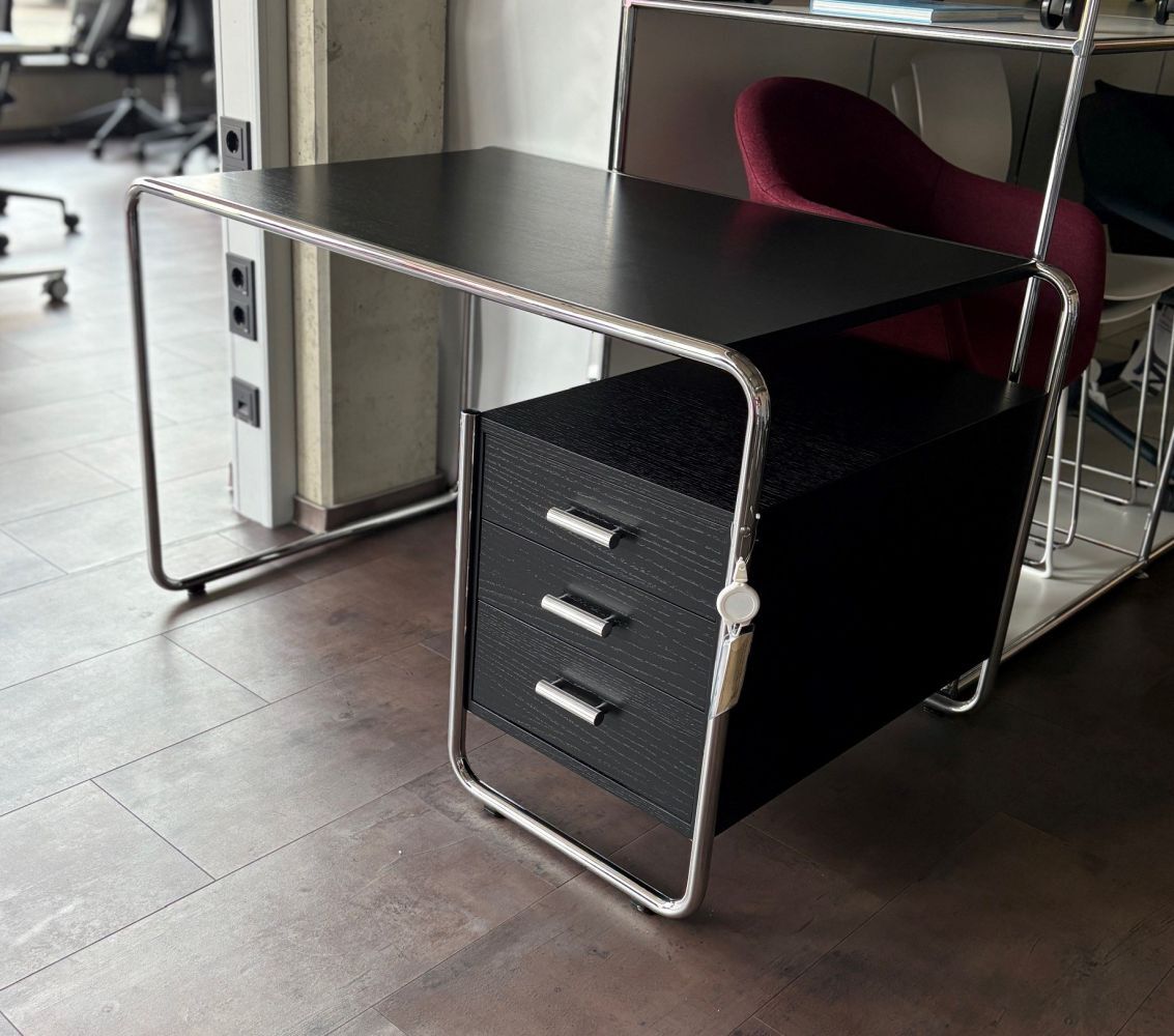 Moderner Schreibtisch mit geschwungenem Metallrahmen und schwarzen Schubladen, passend für ergonomische Büroumgebungen.