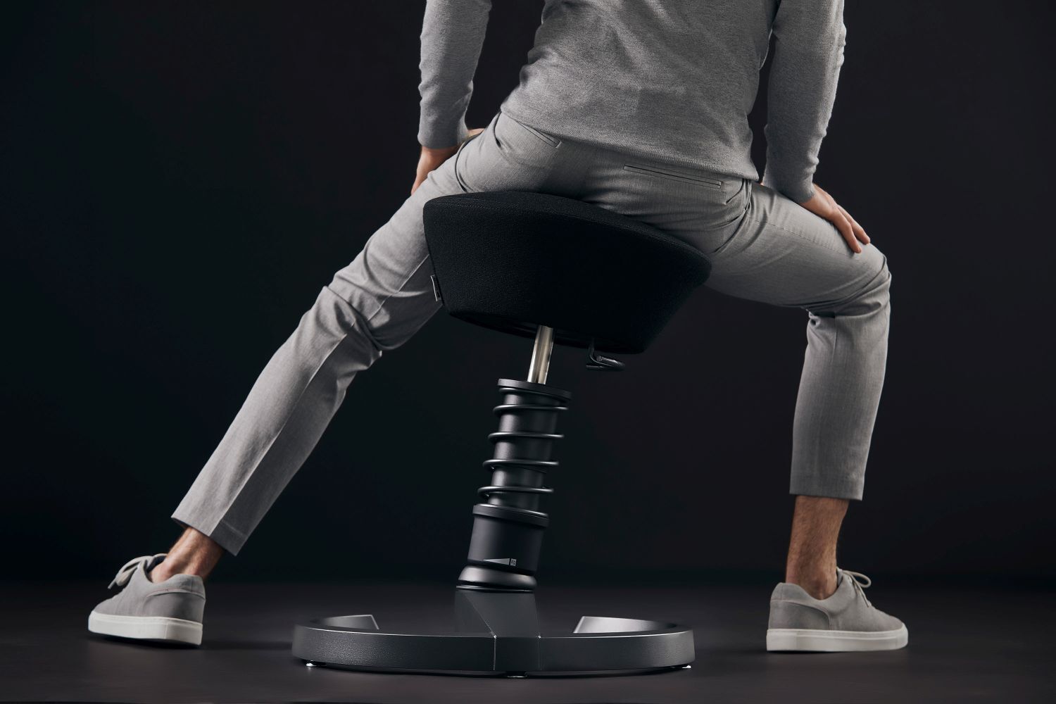 Person auf ergonomischem Hocker für dynamisches Sitzen, betont Flexibilität und Bewegungsfreiheit.