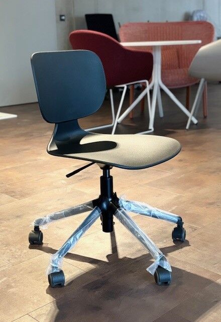 Moderner ergonomischer Bürostuhl mit Rollen, in einem stilvollen Raum mit Holzboden und Designer-Möbeln.