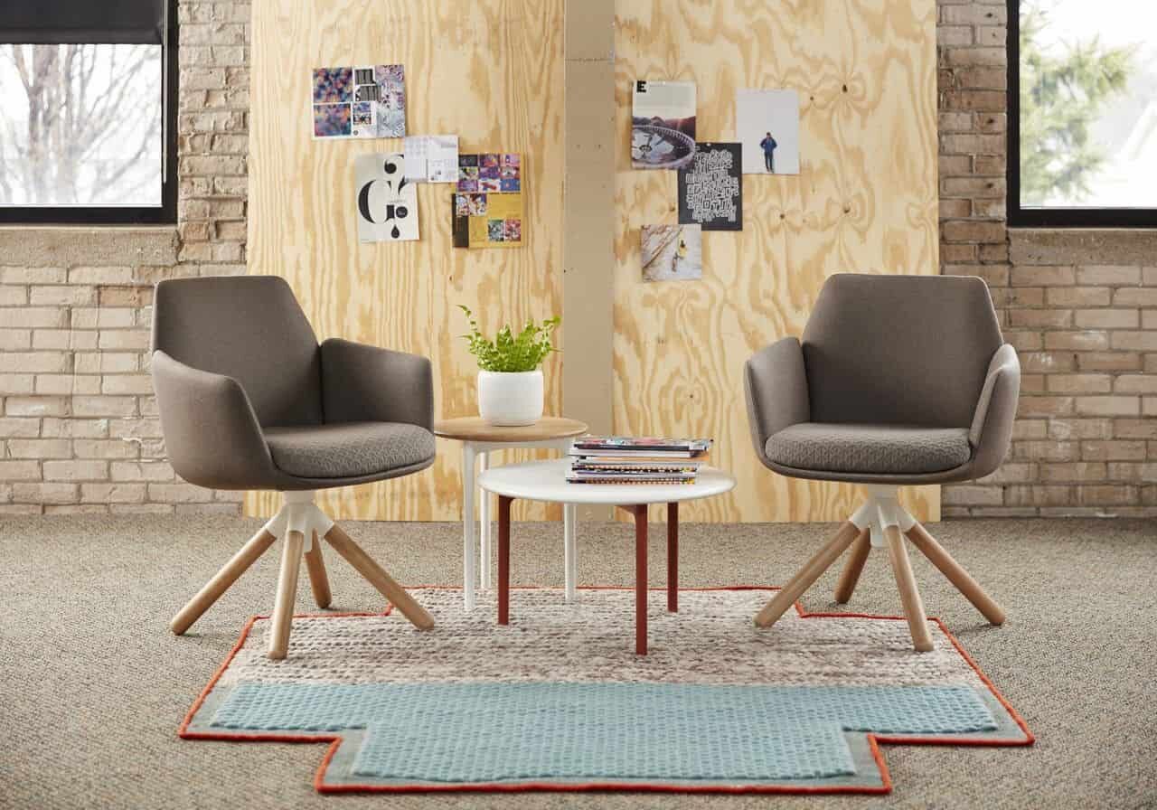 Zwei ergonomische Bürostühle mit Holzakzenten neben einem Beistelltisch in modernem Büroambiente.