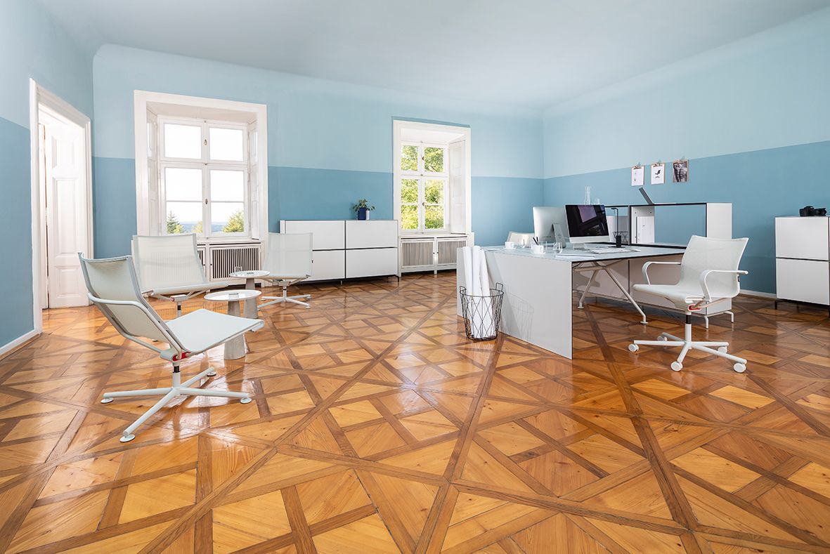 Helles Büro mit ergonomischen Stühlen und moderner Einrichtung, betont durch Holzfußboden und große Fenster.