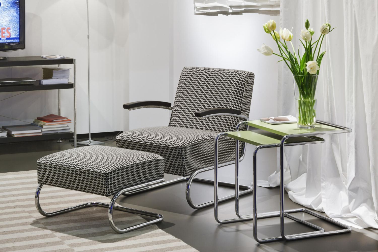 Moderner Sessel mit passendem Hocker, daneben ein kleiner Tisch mit Blumenstrauß im Wohnzimmer.