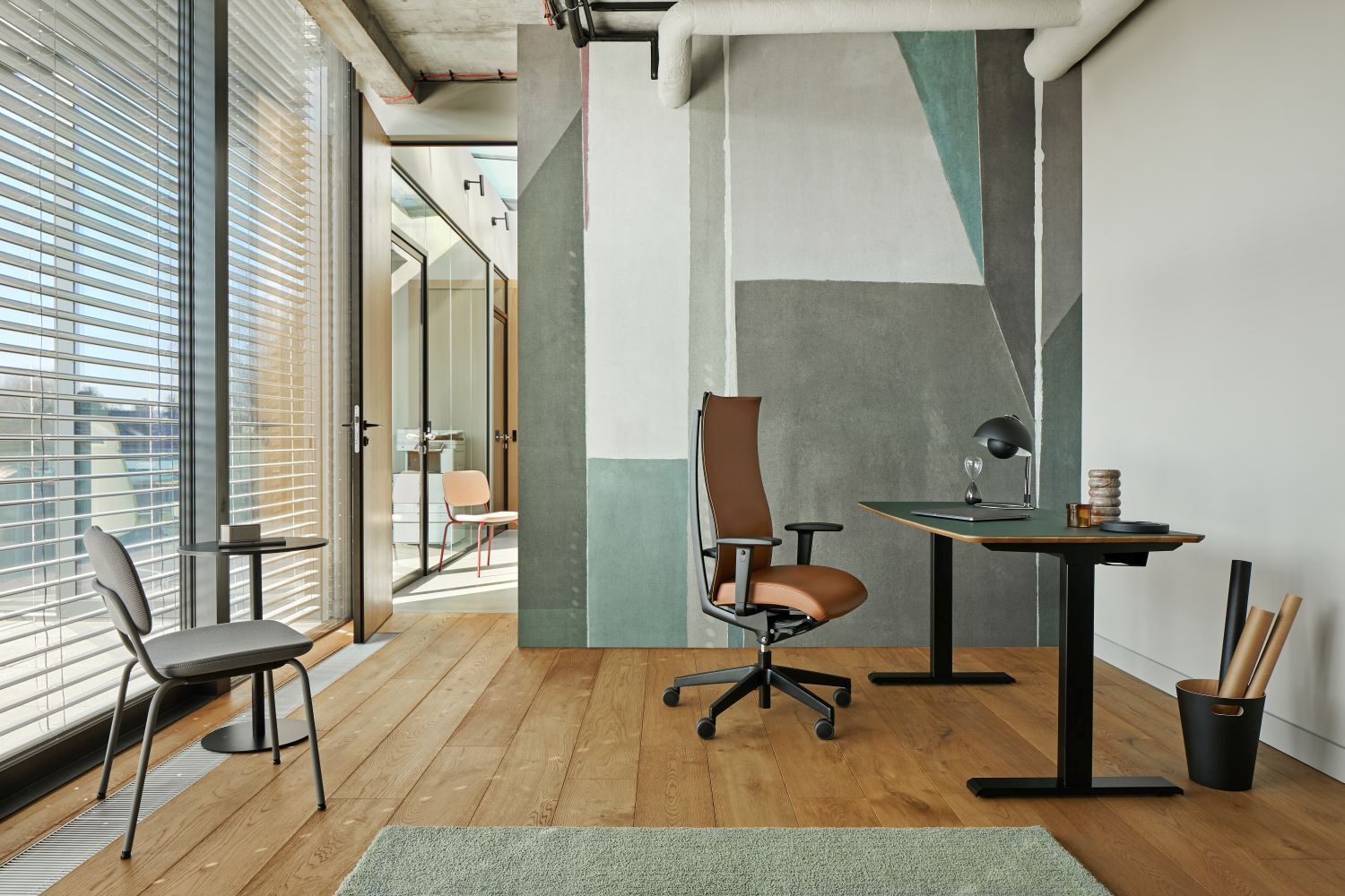 Moderner Büroraum mit ergonomischem Drehstuhl, verstellbarem Schreibtisch und stilvollem Designakzent auf Wand.