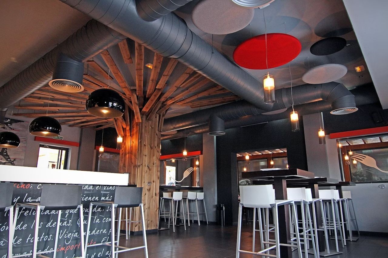 Modernes Café mit einzigartigen Decken- und Beleuchtungselementen, Holzakzenten und hohen weißen Stühlen.