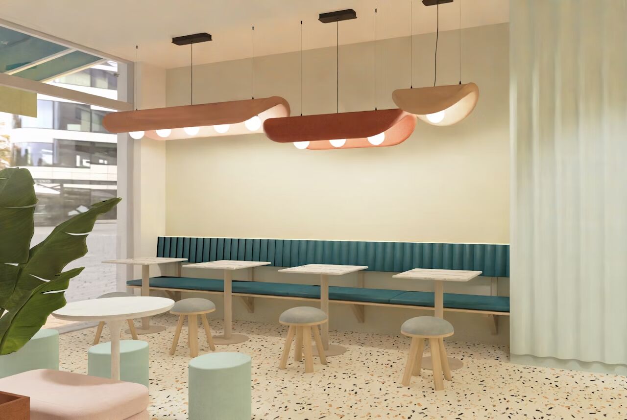 Modernes Café-Interieur mit Hocker, Tischen und gepolsterten Sitzbänken, große Fenster und stilvolle Beleuchtung.