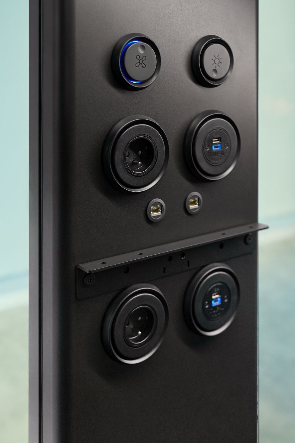 Schwarze Steckdoseleiste mit USB- und Steckdosenanschlüssen, sowie beleuchteten Tasten für Lüfter und Beleuchtung.