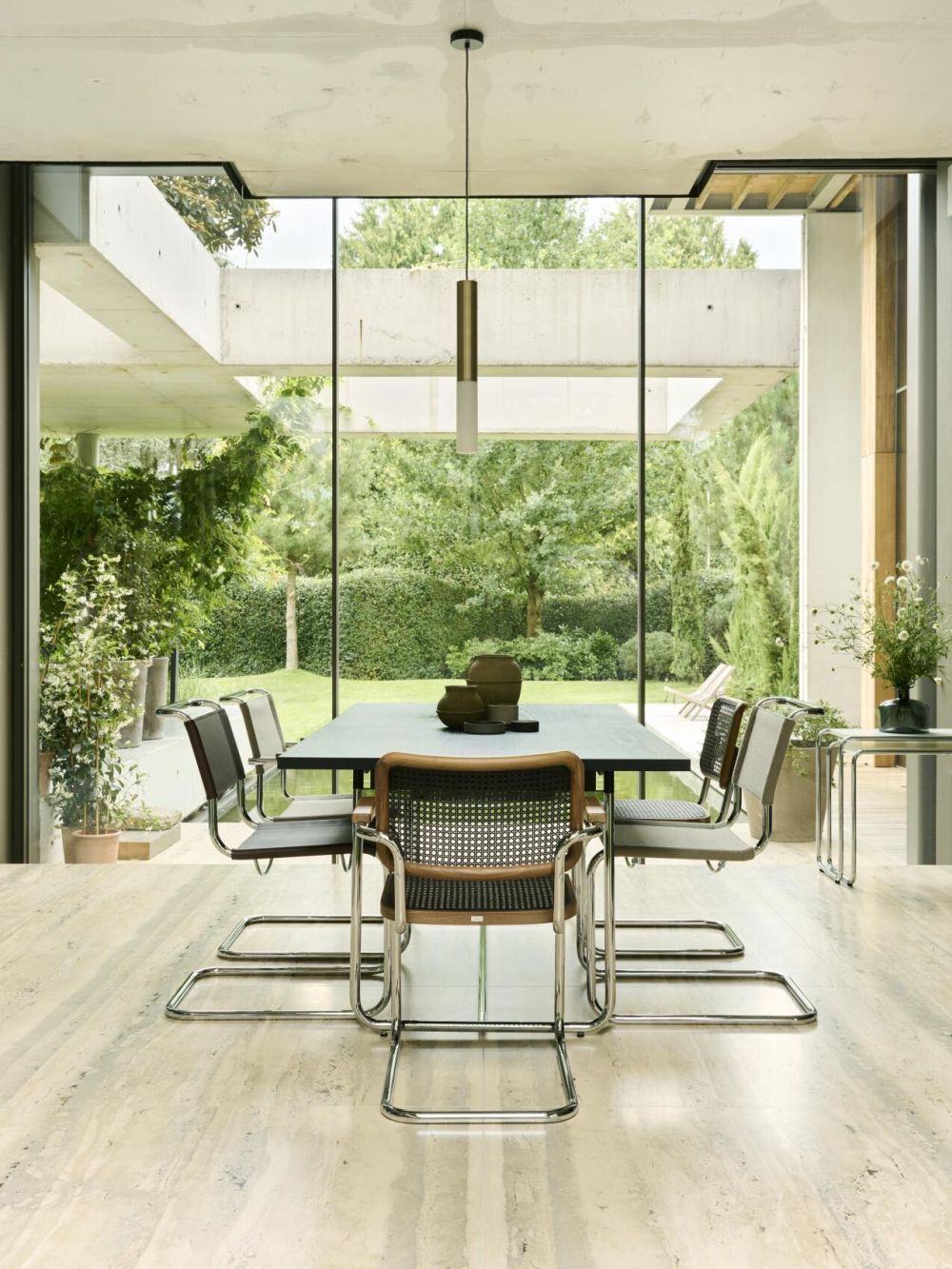 Moderner Esszimmerbereich mit Tisch und Stühlen, Blick auf Garten durch große Fenster.