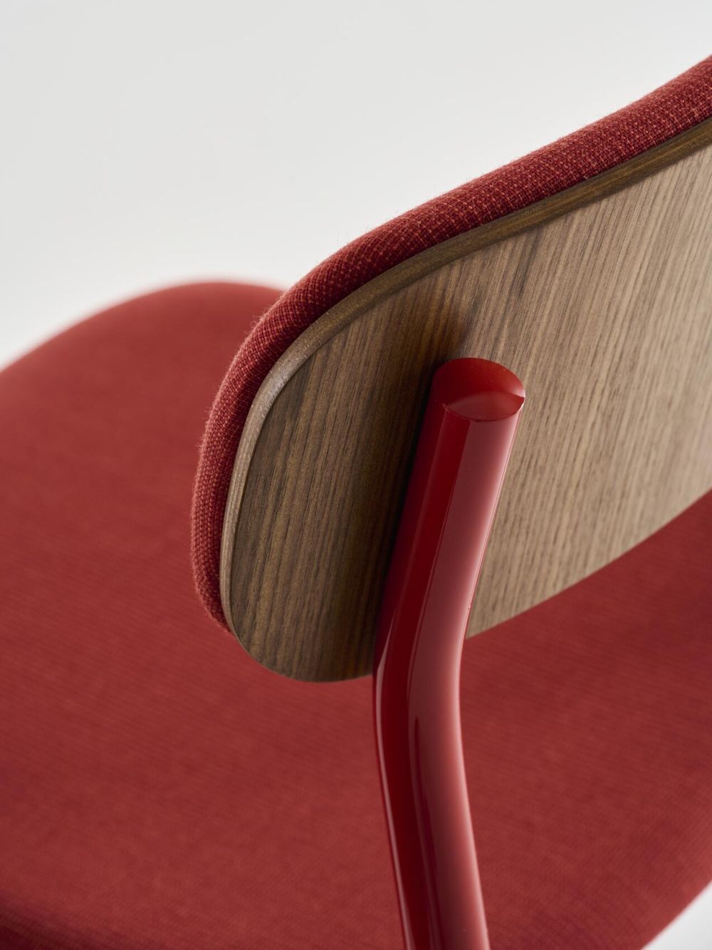 Roter ergonomischer Stuhl mit Holzelementen und Stoffbezug, moderne Designmerkmale für dynamisches Sitzen.