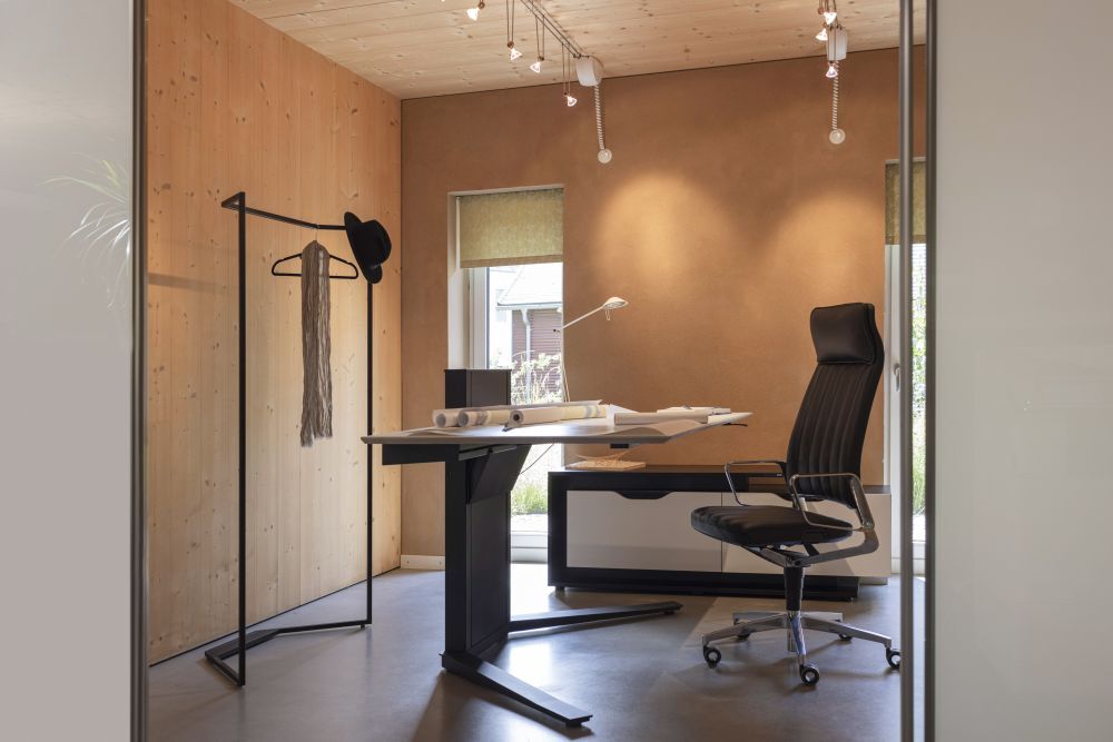 Modernes Büro mit ergonomischem Stuhl und höhenverstellbarem Schreibtisch, natürlicher Beleuchtung und Holzwänden.