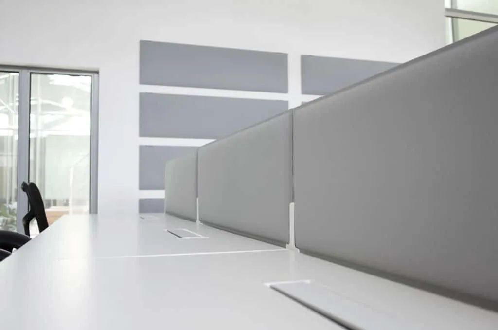 Minimalistisches Büro mit ergonomischen Schreibtischen und grauen Trennwänden, ideal für produktives Arbeiten.