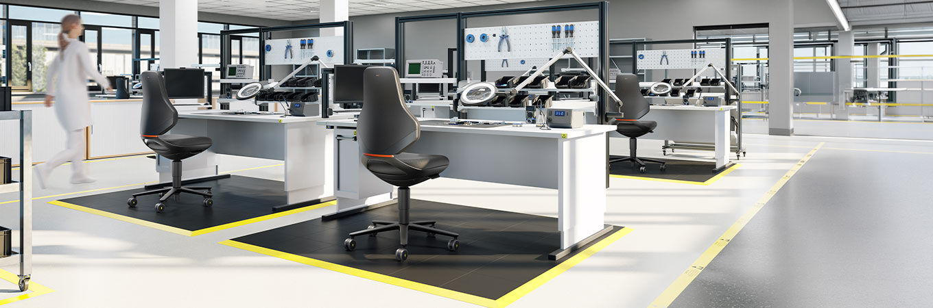 Moderne Büroumgebung mit ergonomischen Stühlen, leeren Schreibtischen und industrieller Ausstattung für dynamisches Arbeiten.