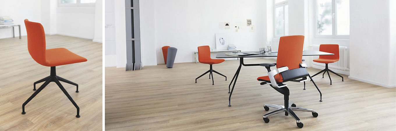 Moderne Besucherstühle Wilkhahn Pep mit orangefarbenen Polstern in einem hellen, minimalistischen Raum mit Holzboden und großem Fenster.