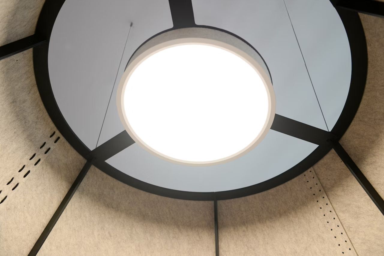 Innenansicht einer modernen Beleuchtungslösung mit kreisförmiger Leuchte in einem abgedämmten Raum.