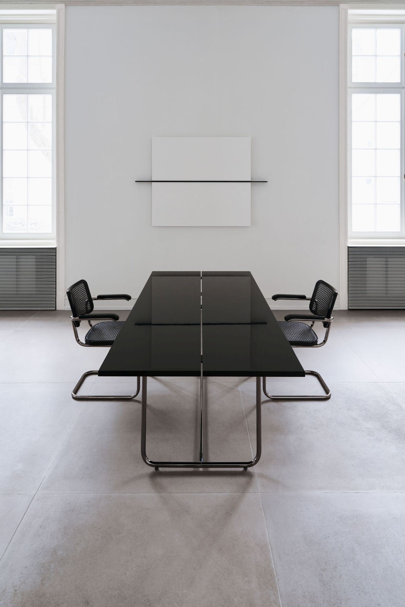 Moderne Besprechungstisch-Szene mit zwei ergonomischen Stühlen in einem minimalistischen, lichtdurchfluteten Raum.