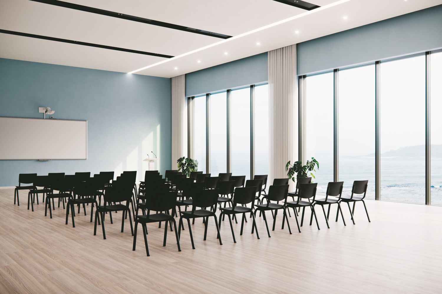 Moderner Konferenzraum mit schwarzen Stühlen, großen Fenstern und Blick aufs Meer.