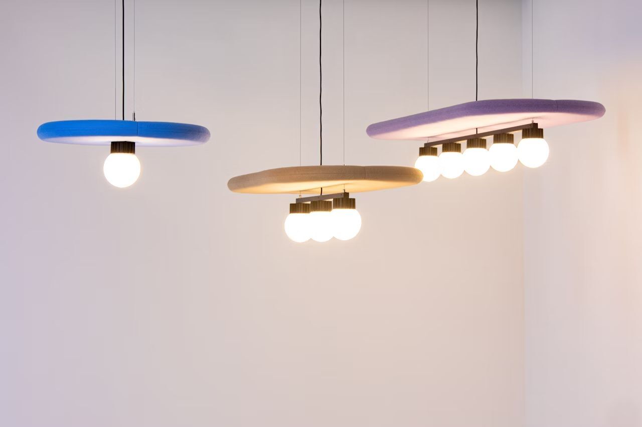 Drei moderne, schlichte Hängelampen mit runden Rahmen und Energiesparlampen in einem minimalistisch gestalteten Raum.