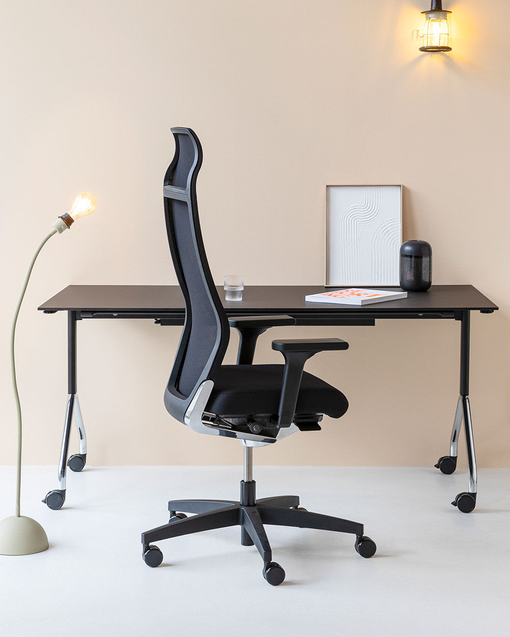 Ergonomischer Bürostuhl mit hohem Rückenlehnen-Design vor einem modernen Schreibtisch mit Dekorationen.