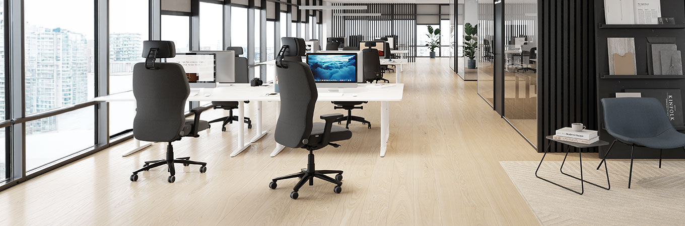 Zwei Personen sitzen auf ergonomischen Stühlen vor mehreren Computermonitoren in einem Kontrollraum.