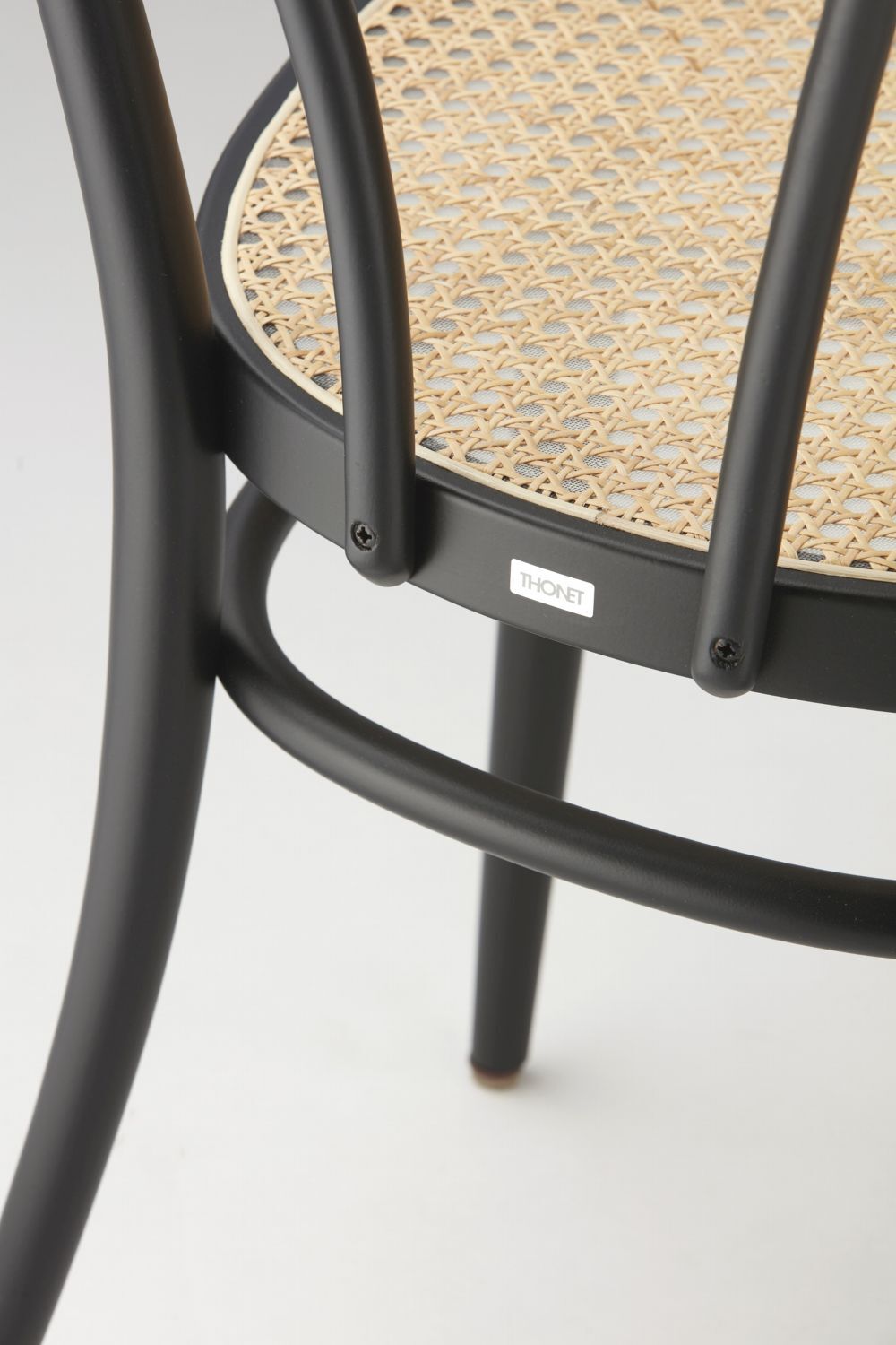 Nahaufnahme eines Thonet-Stuhls mit schwarzem Rahmen und geflochtener Sitzfläche.