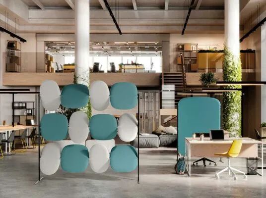 Modernes Büro mit ergonomischen Möbeln, weißen und blauen Akustikpaneelen und großen Pflanzen.