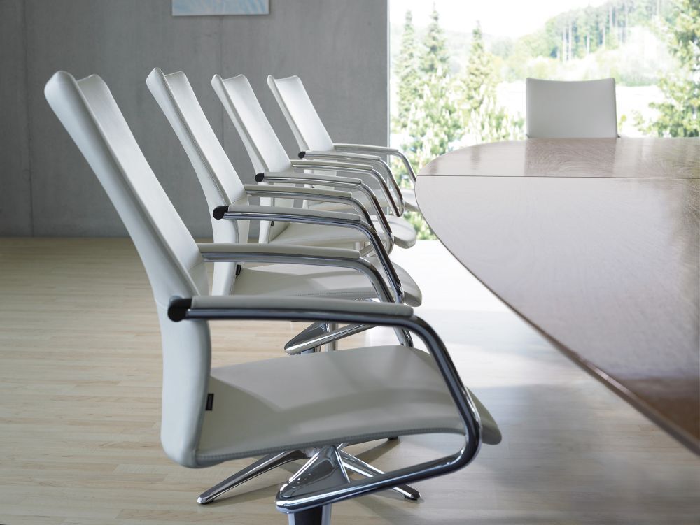 Moderne, ergonomische Bürostühle in einem hellen Konferenzraum mit großem Holztisch, ausgerichtet für Meetings.