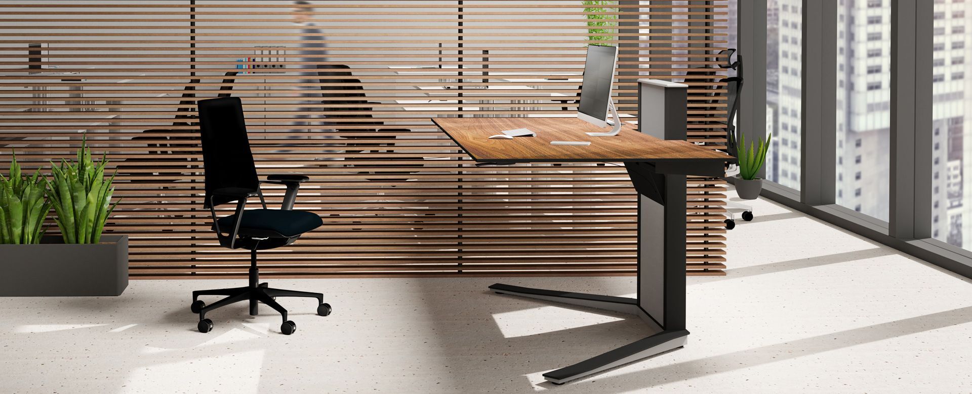 Modernes Büro mit ergonomischem Stuhl, höhenverstellbarem Schreibtisch und großen Fenstern für viel Tageslicht.