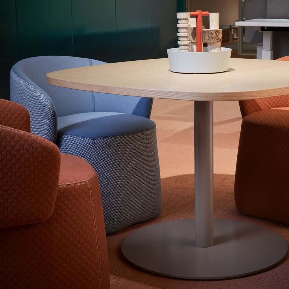 Runder Tisch mit modernen Polsterstühlen in Blau und Braun, dekoriert mit einem stilvollen Tischmittelstück.