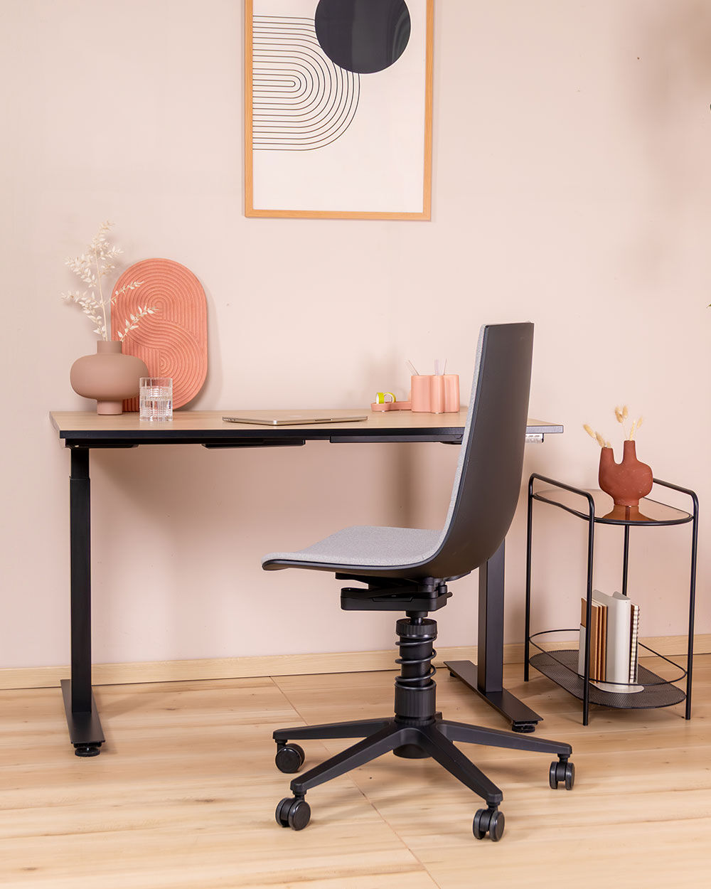 Moderner ergonomischer Bürostuhl mit höhenverstellbarem Schreibtisch in minimalistischem Homeoffice-Design, dekoriert mit Kunst und Pflanzen.
