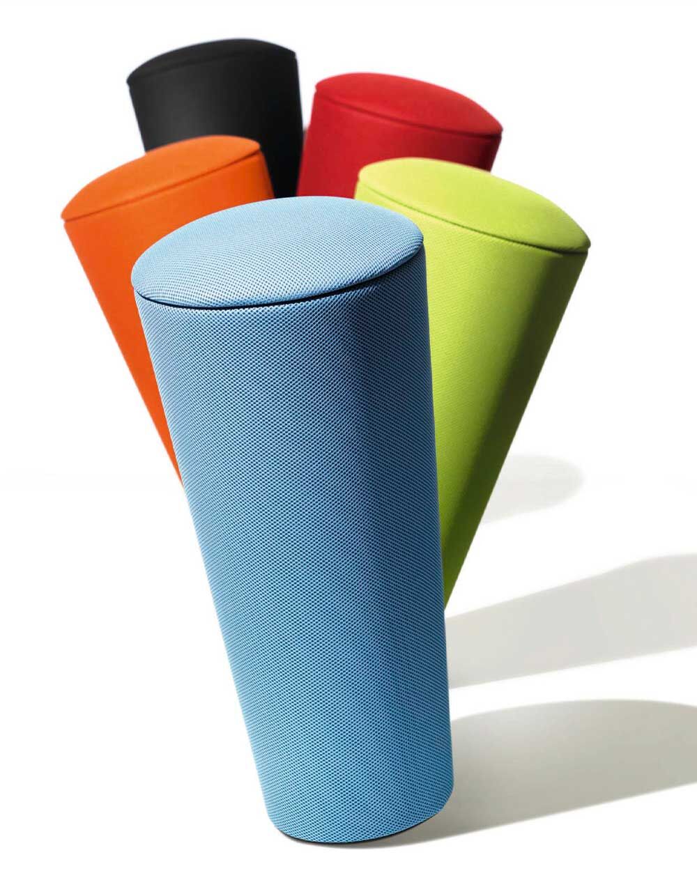 Fünf ergonomische Hocker in verschiedenen Farben: blau, grün, rot, orange und schwarz, aufrecht nebeneinander stehend.