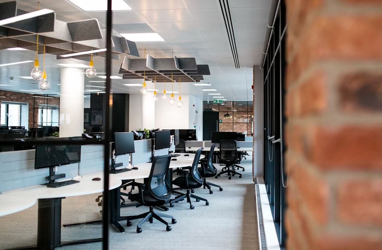 Modernes Büro mit ergonomischen Stühlen, großen Schreibtischen und Akustikdecken, optimiert für dynamisches Sitzen.