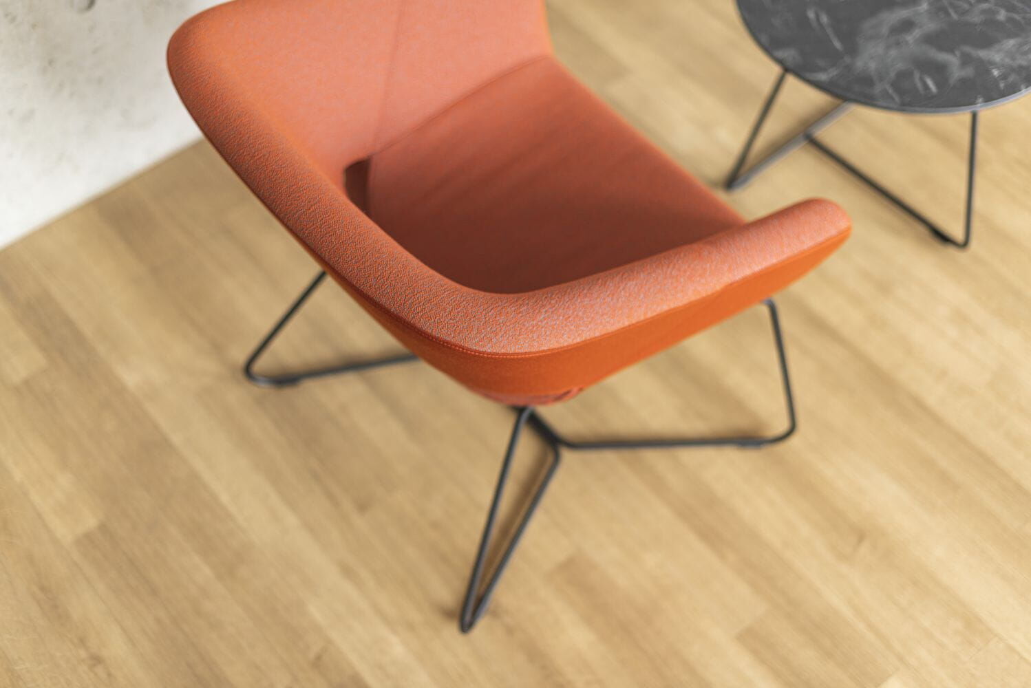 Roter ergonomischer Stuhl mit Metallbeinen auf Holzfußboden neben einem kleinen runden Tisch.