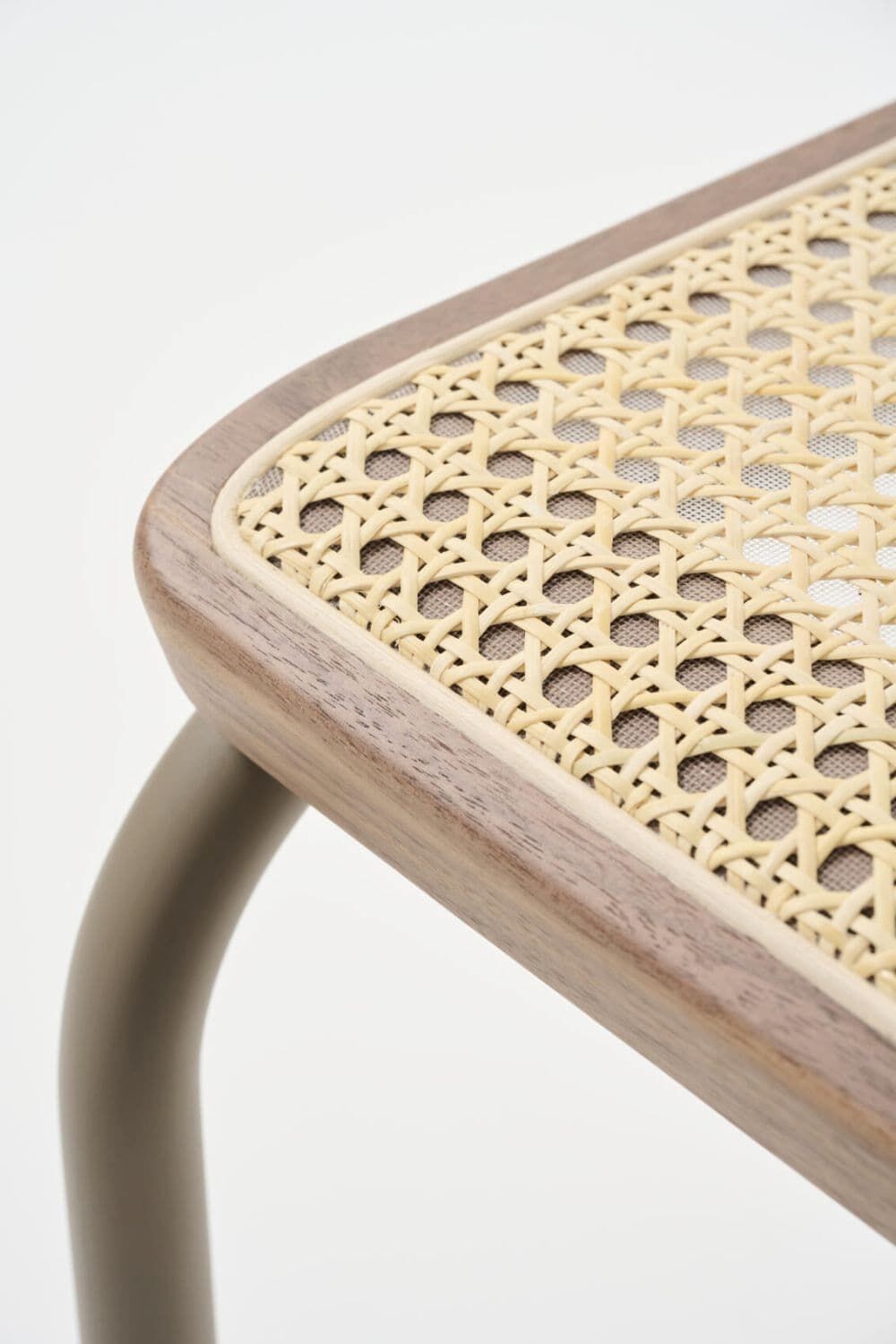 Nahaufnahme eines ergonomischen Stuhlbeins mit geflochtener Sitzfläche aus Holz und Rohrgeflecht.