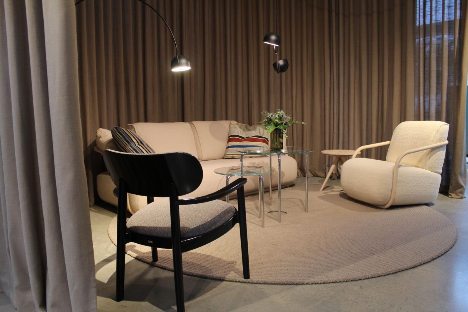 Moderner Wohnbereich mit Sessel, Sofa, Glas-Couchtisch und Vorhängen für eine gemütliche Atmosphäre.