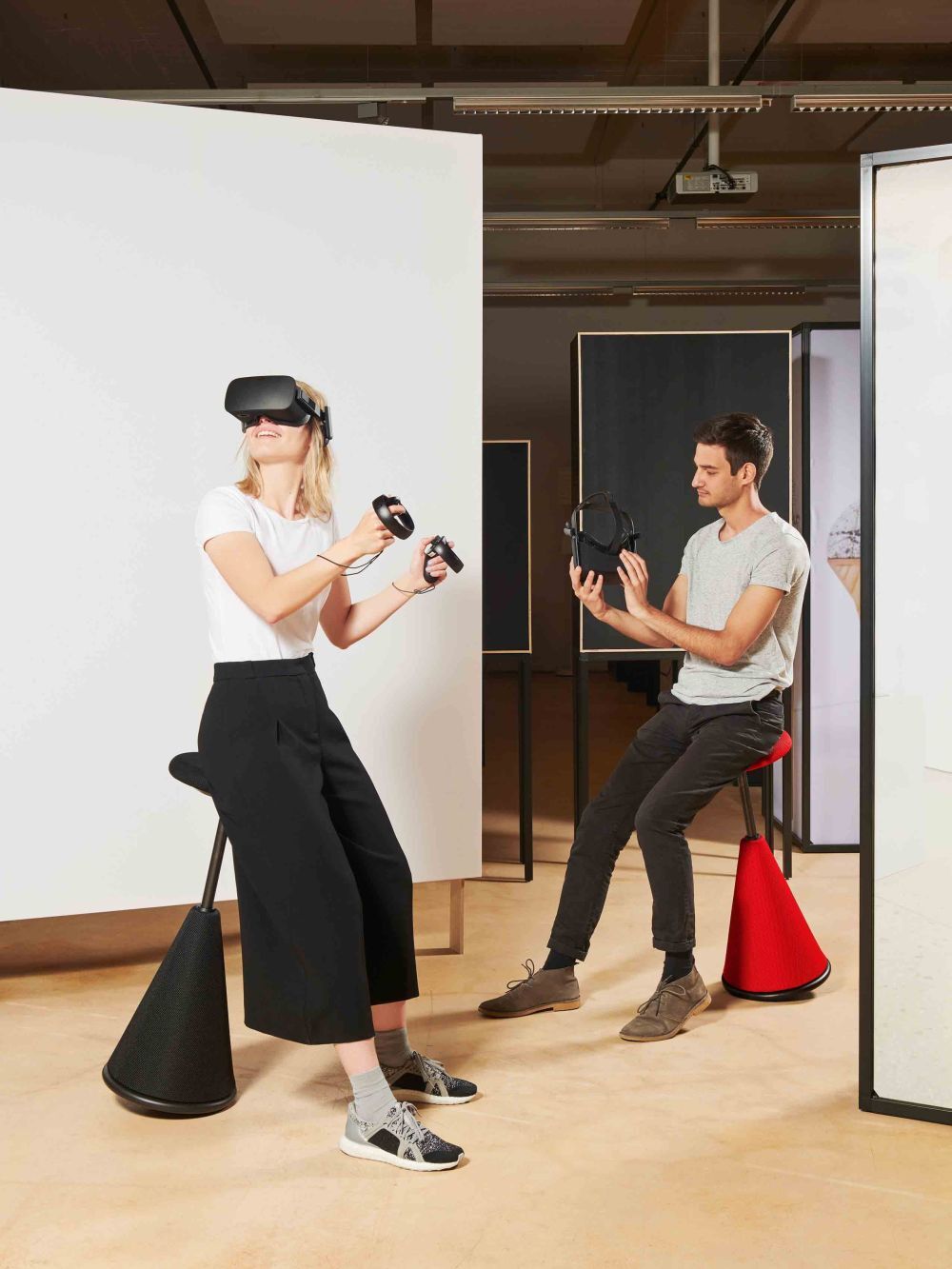 Zwei Personen auf ergonomischen Hockern mit VR-Brillen, in einem modernen Büroambiente, erleben dynamisches Sitzen.