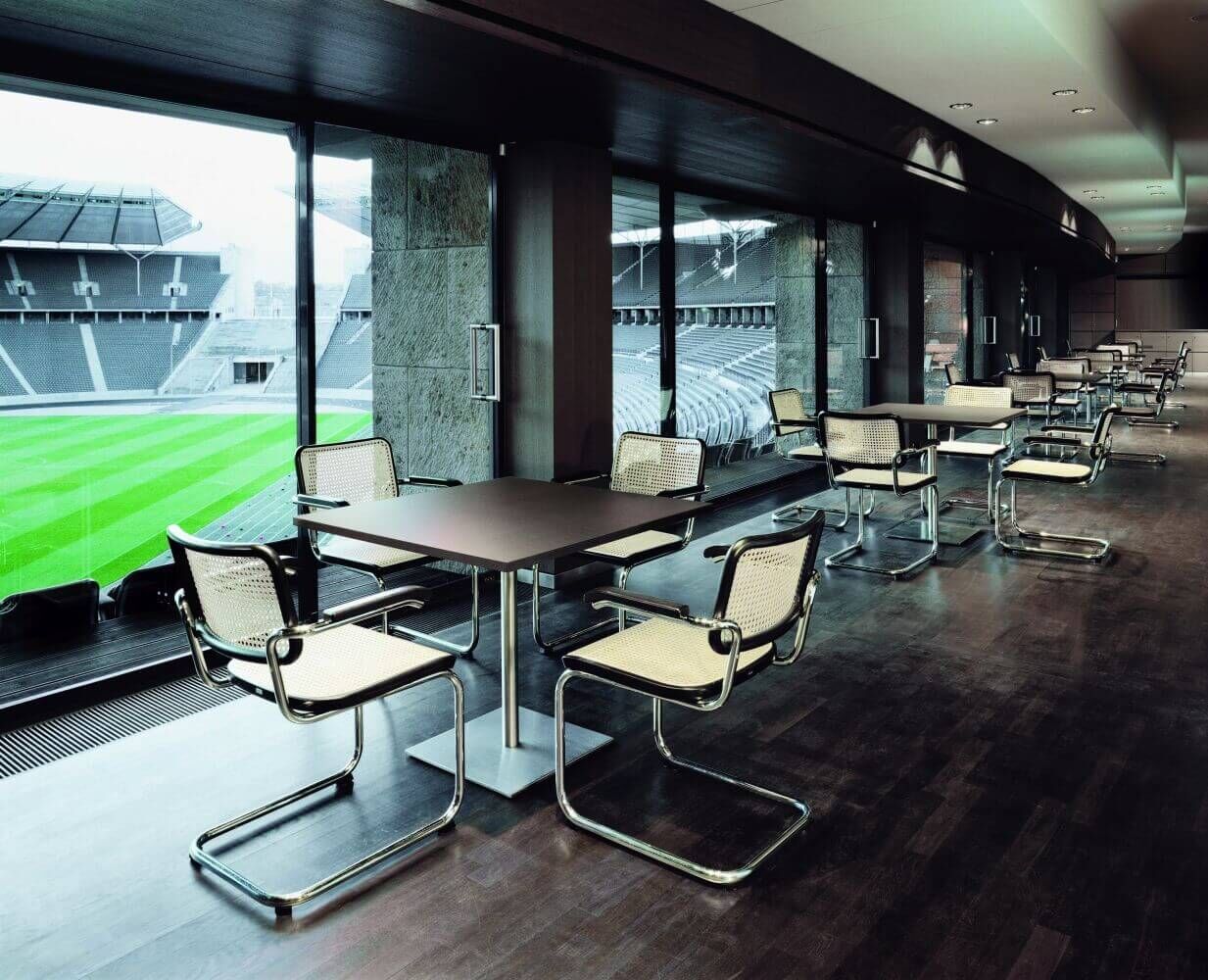 Moderne ergonomische Stühle und Tische in einem stilvollen Raum mit Blick ins Stadion.
