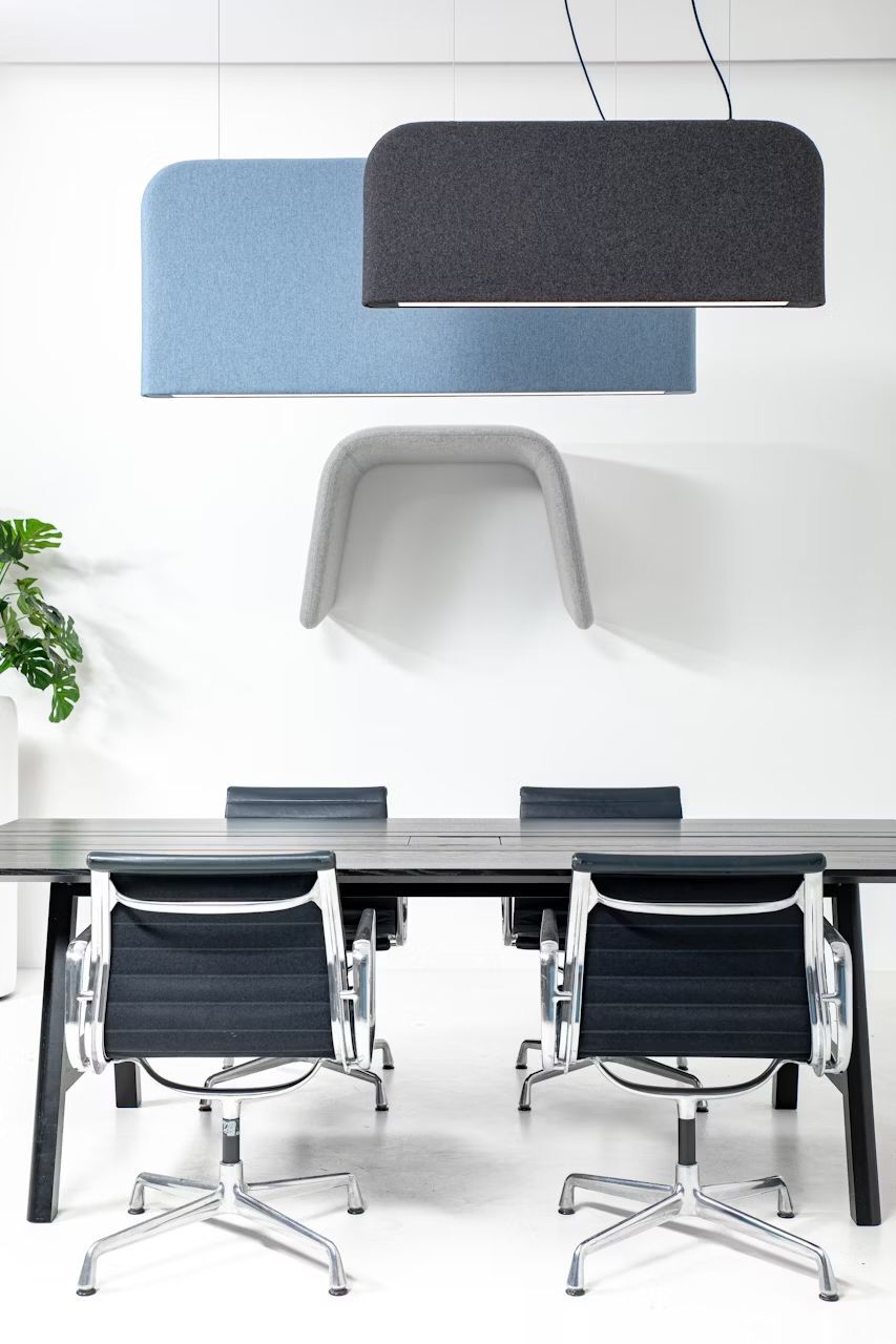 Moderner Konferenzraum mit ergonomischen schwarzen Bürostühlen und eleganten Akustikpaneelen an der Wand.