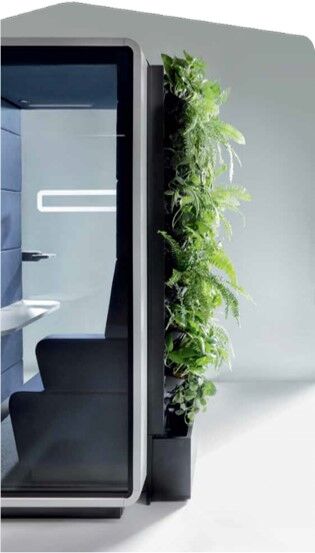 Ergonomischer Arbeitsraum mit integrierter Sitzgelegenheit und grüner Pflanzwand für ein gesundes Büroklima.