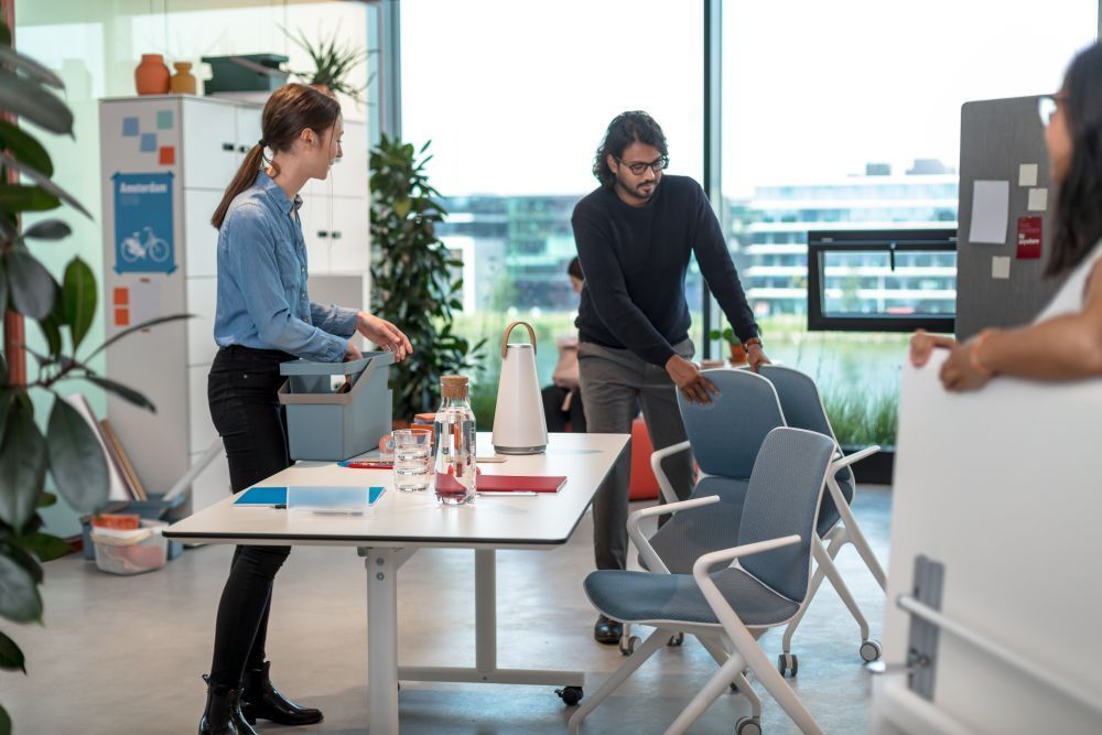 Menschen in modernem Büro testen ergonomische Stühle, die dynamisches und gesundes Sitzen fördern.