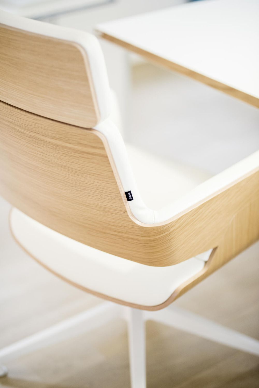 Nahaufnahme eines hochwertigen, ergonomischen Bürostuhls aus Holz und Weiß, betont Funktionalität und Design.