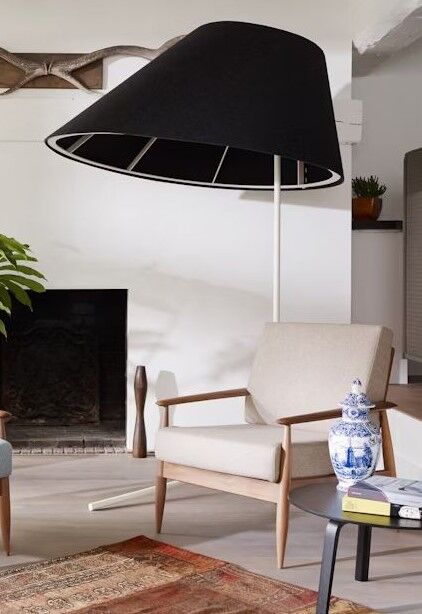 Moderner Raum mit beige Sessel, großer Stehlampe, Kamin und Dekorvase auf Beistelltisch.