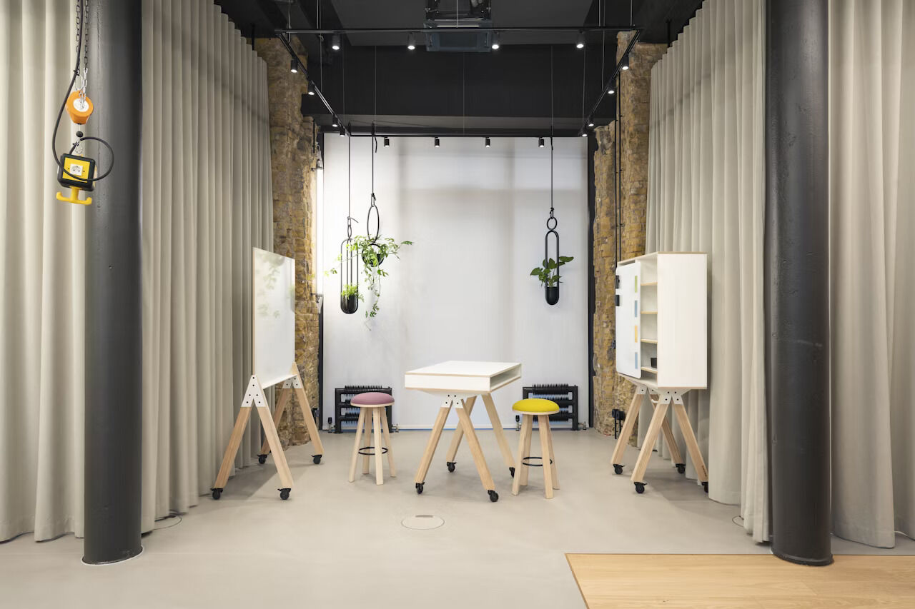 Moderner Raum mit ergonomischen Stühlen, Tabletts und hängenden Pflanzen, ideal für dynamisches Sitzen.