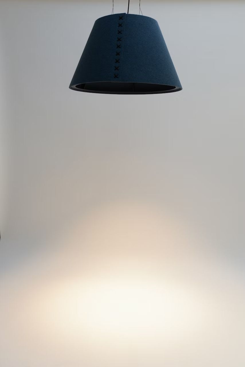 Moderne, blaue Hängelampe mit Kreuzstichmuster an einer neutralen Wand montiert, strahlt warmes Licht aus.