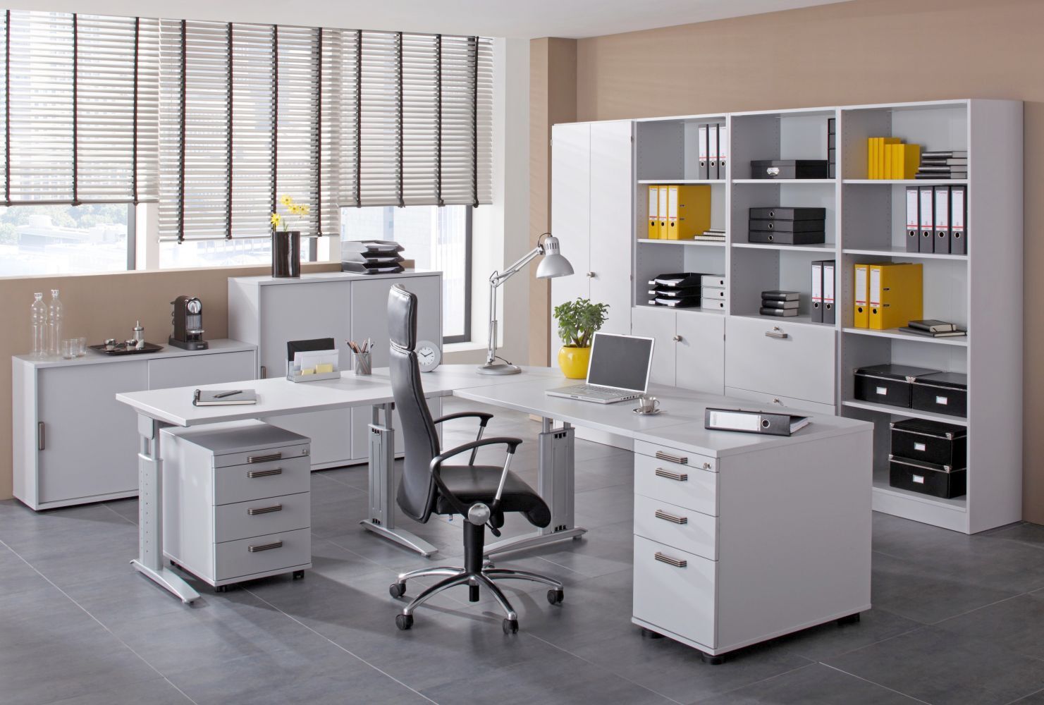 Modernes, ergonomisches Büro mit weißem Schreibtisch, komfortablem Stuhl, Laptop und Regalen voller Aktenordner.