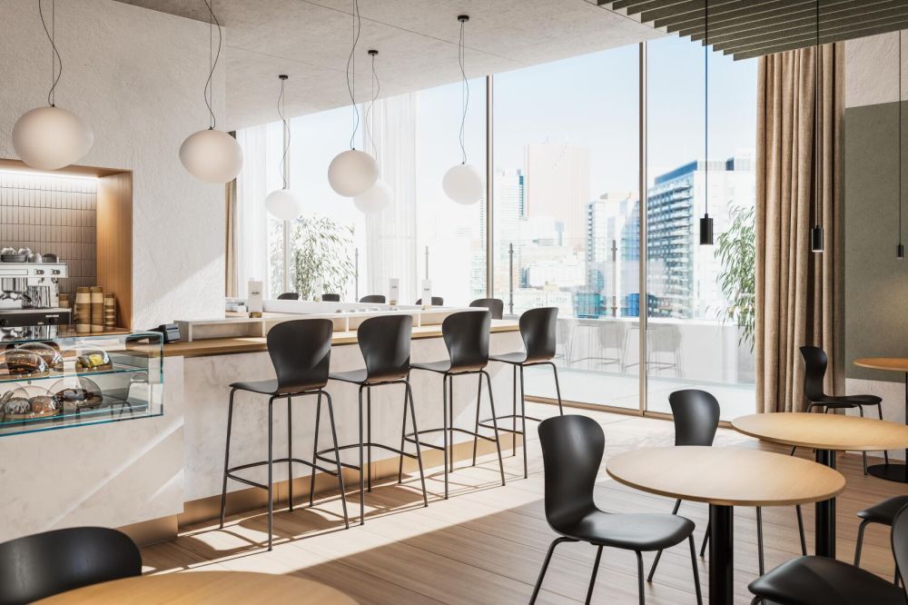 Modernes Café mit großen Fenstern, Barhockern und Hängelampen, im Hintergrund Stadtblick.