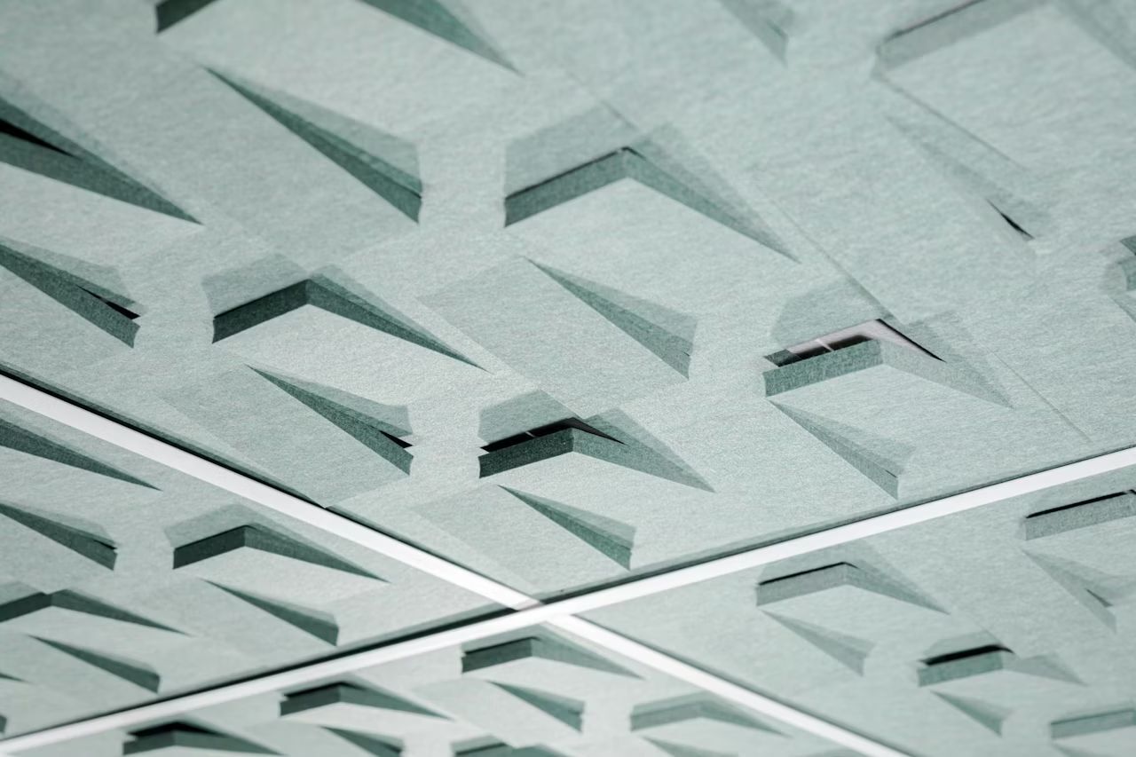 Nahaufnahme einer modernen, geometrisch gestalteten Akustikdecke mit dreieckigen Mustern in minimalistischer Ästhetik.