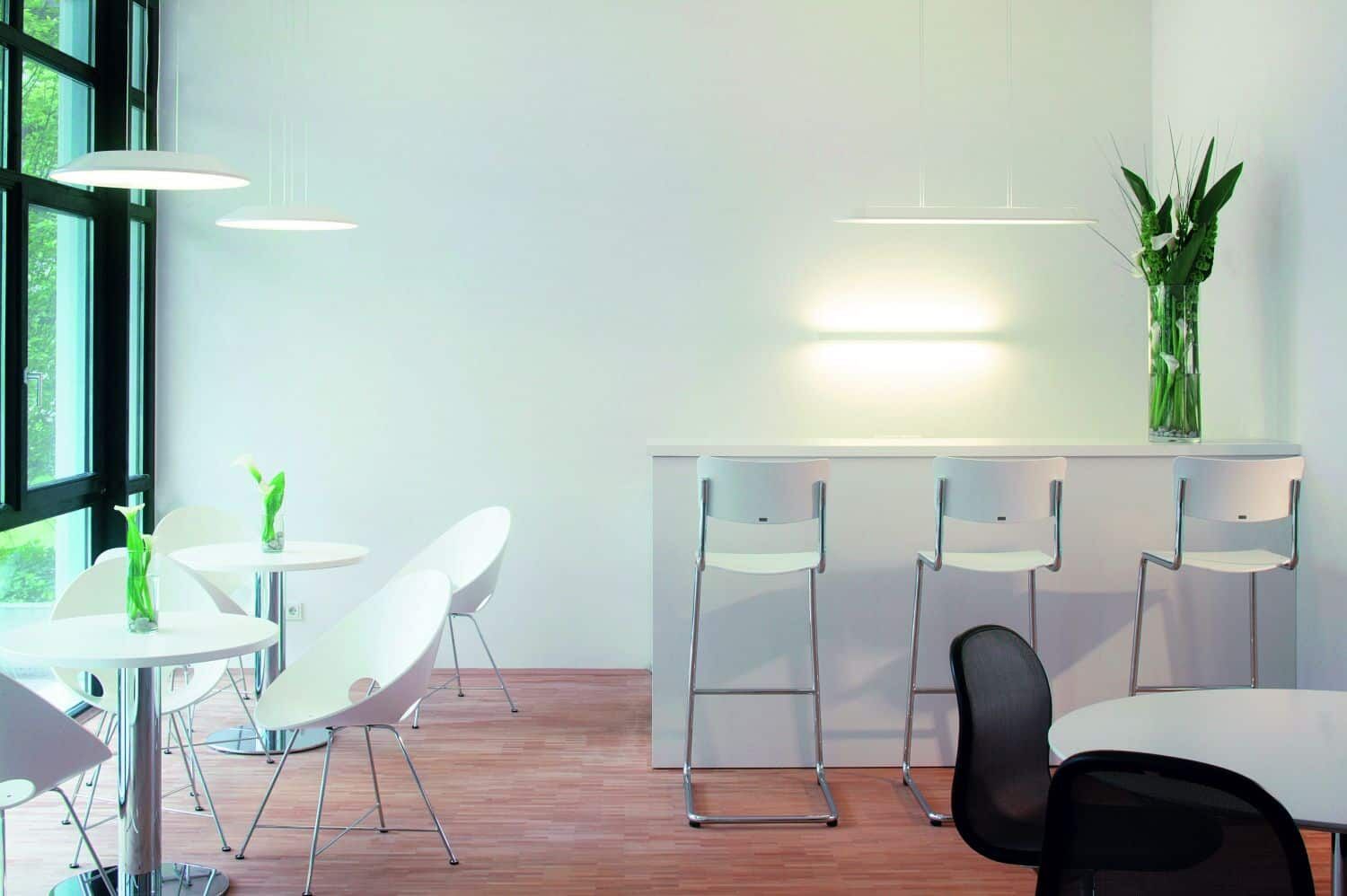 Moderne Cafeteria mit weißen Stühlen, Tischen und minimalistischer Dekoration in heller, einladender Umgebung.