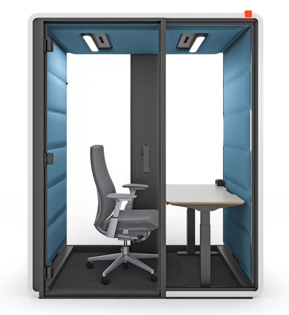 Schallisolierte Arbeitskabine mit ergonomischem Bürostuhl und höhenverstellbarem Tisch für konzentriertes Arbeiten.